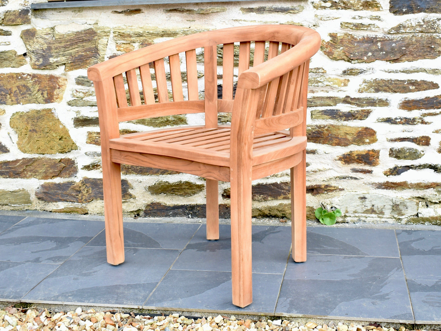 side angle of a curved teak banana armchair on a patio