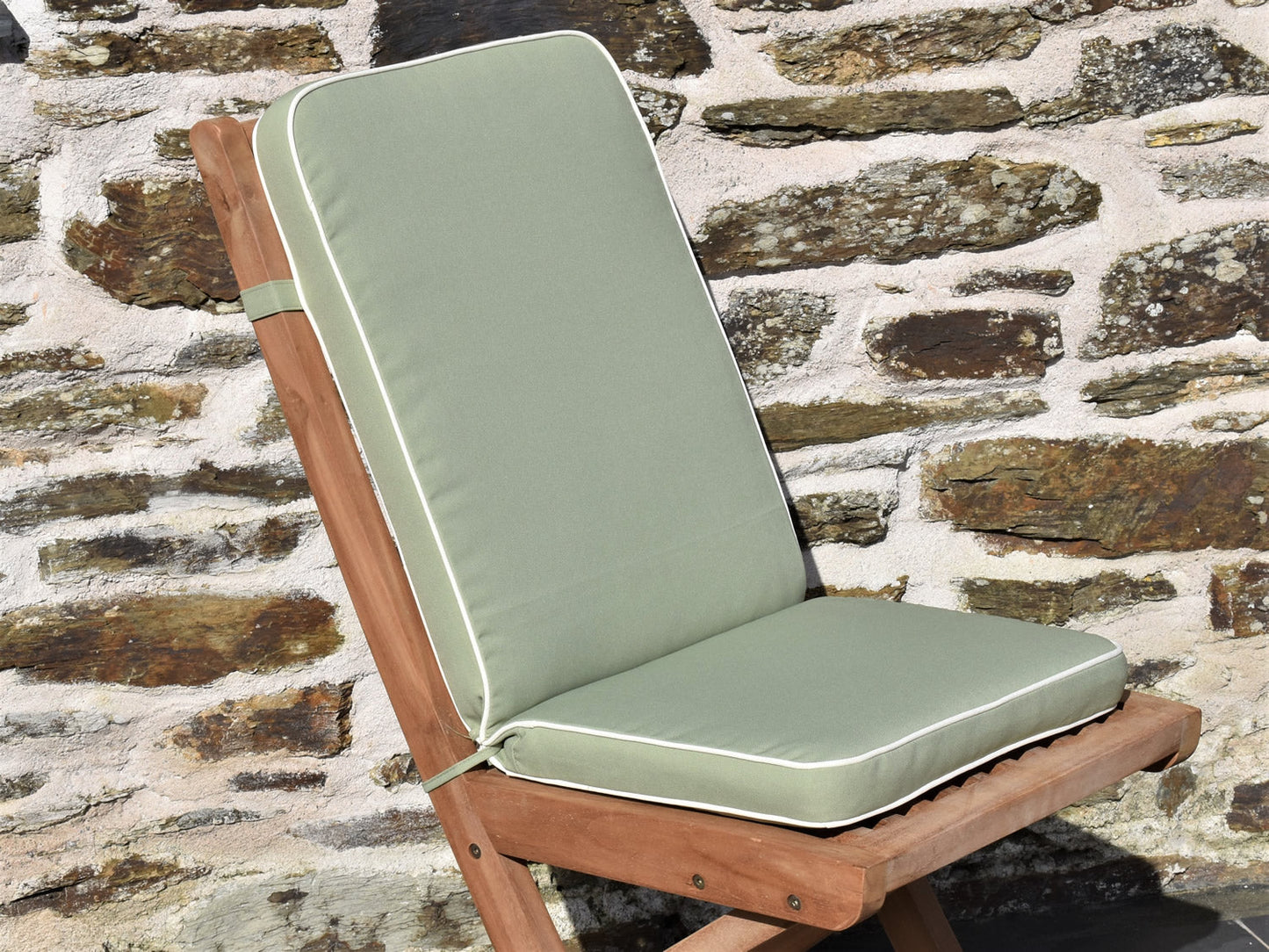 close-up detail of light olive green luxury folding seat pad and back cushion, finished with contrast white fabric piping and matching fabric ties and back strap