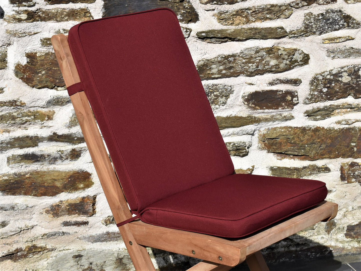 close-up burgundy colour fabric folding outdoor pad/back cushion, finished with matching fabric piping, ties and back strap
