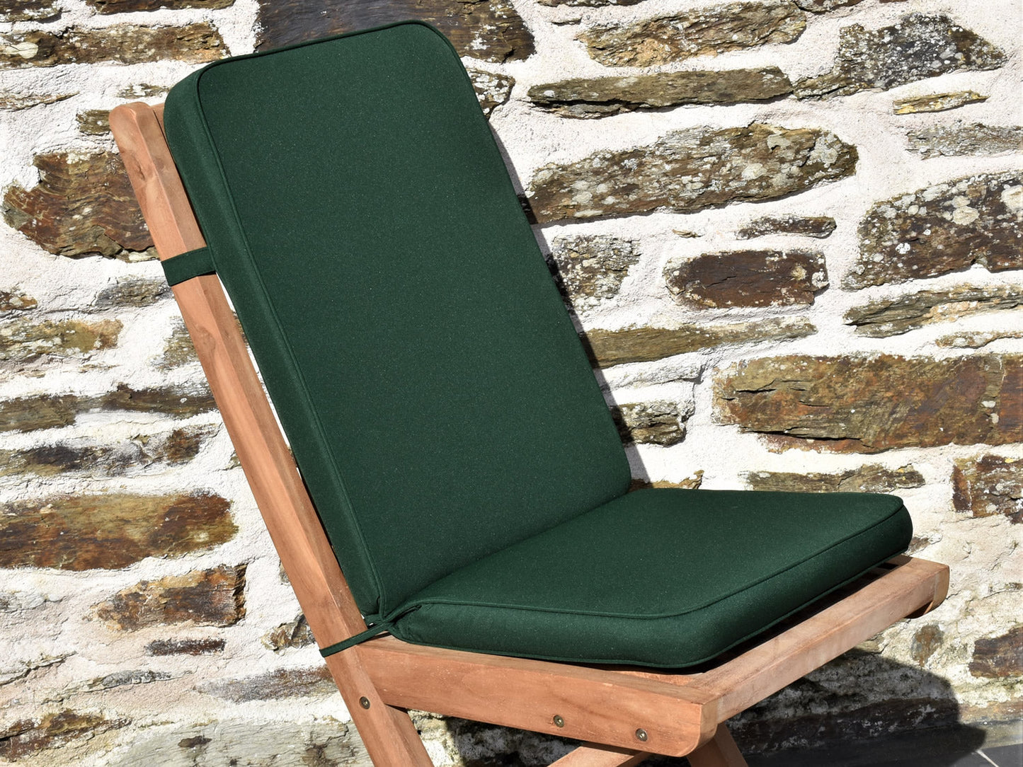 close-up dark green fabric outdoor folding pad/back cushion, finished with matching fabric piping, ties and back strap