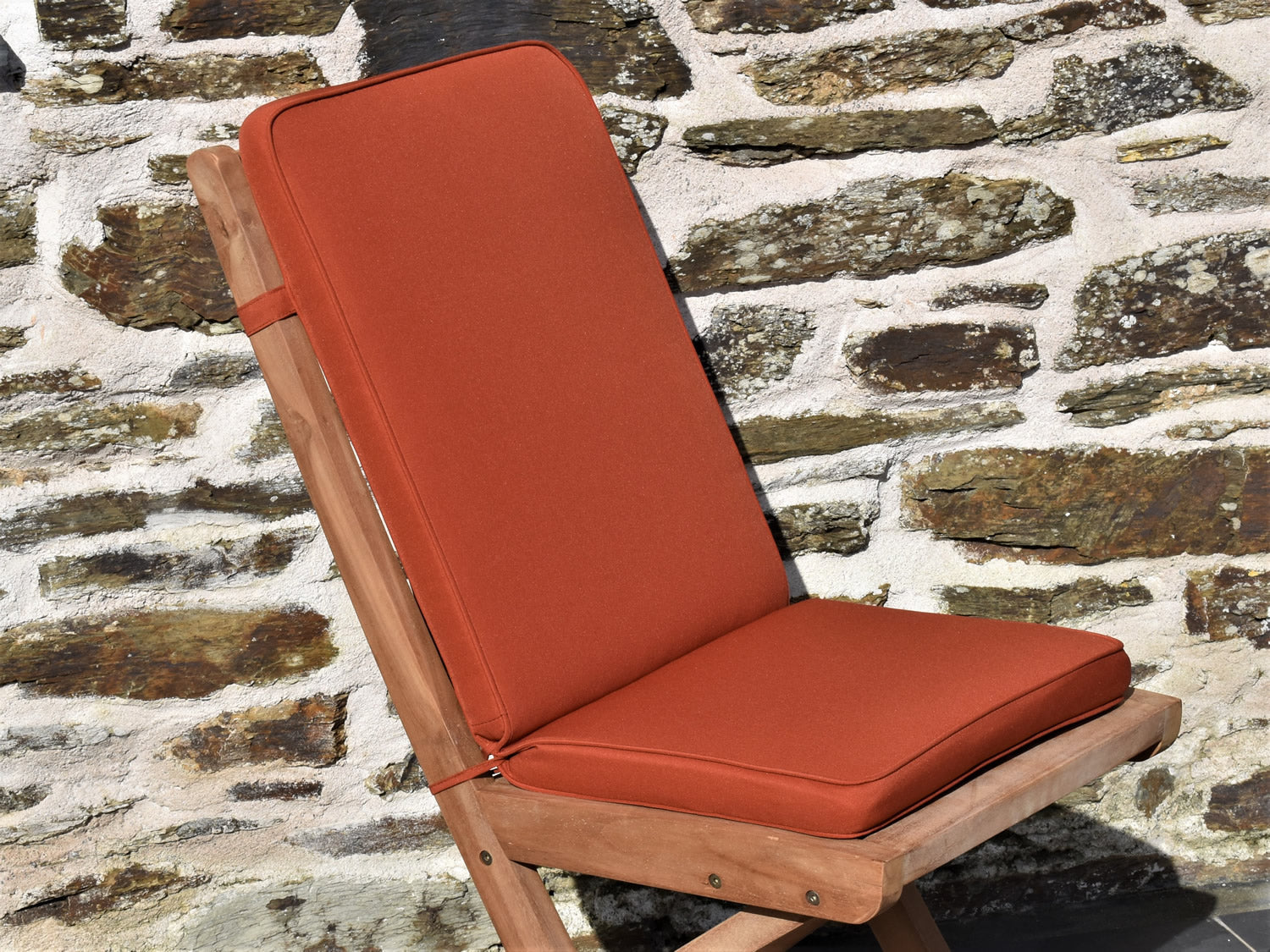 Close-up terracotta orange colour fabric garden folding pad/back cushion, finished with matching colour piping, ties and back strap