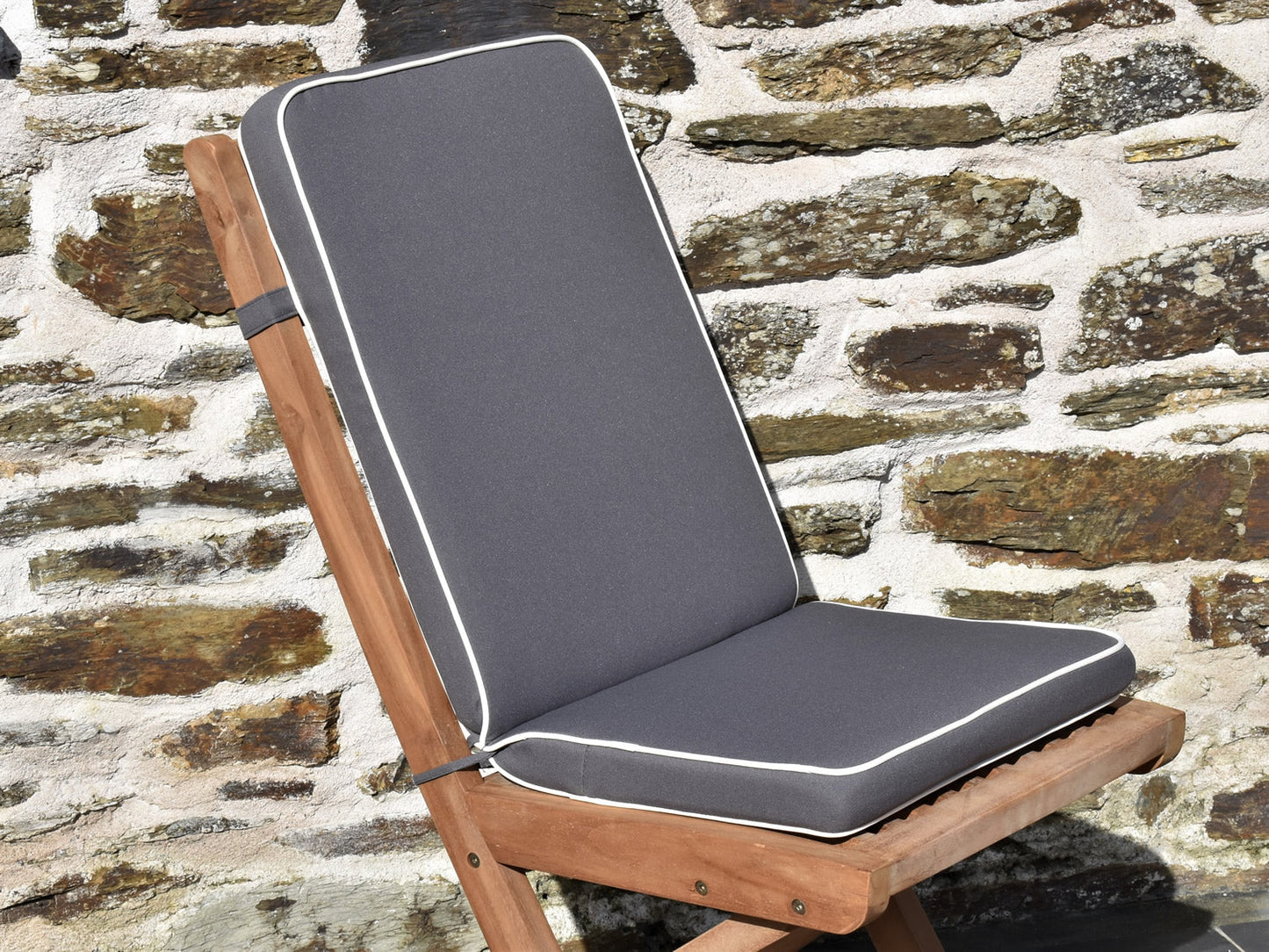 close-up detail of luxury grey folding seat pad and back cushion, finished with contrast white piping and matching fabric ties and back strap. 