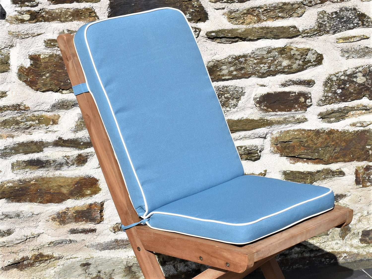 close-up detail of luxury light blue folding seat pad and back cushion, finished with contrast white piping and matching fabric ties and back strap