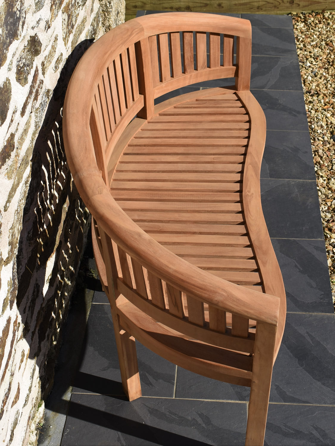 Side profile of a half-moon teak garden bench showcasing its elegant curved design