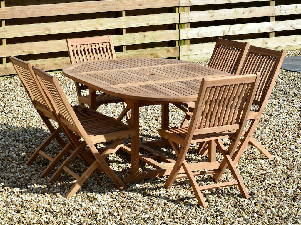 teak 120x180cm extended garden dining table shown with six folding dining chairs
